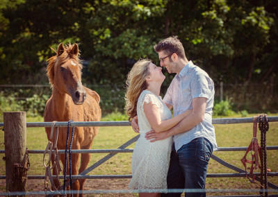 couple kissing while horse looks on by Samantha Brown Photography